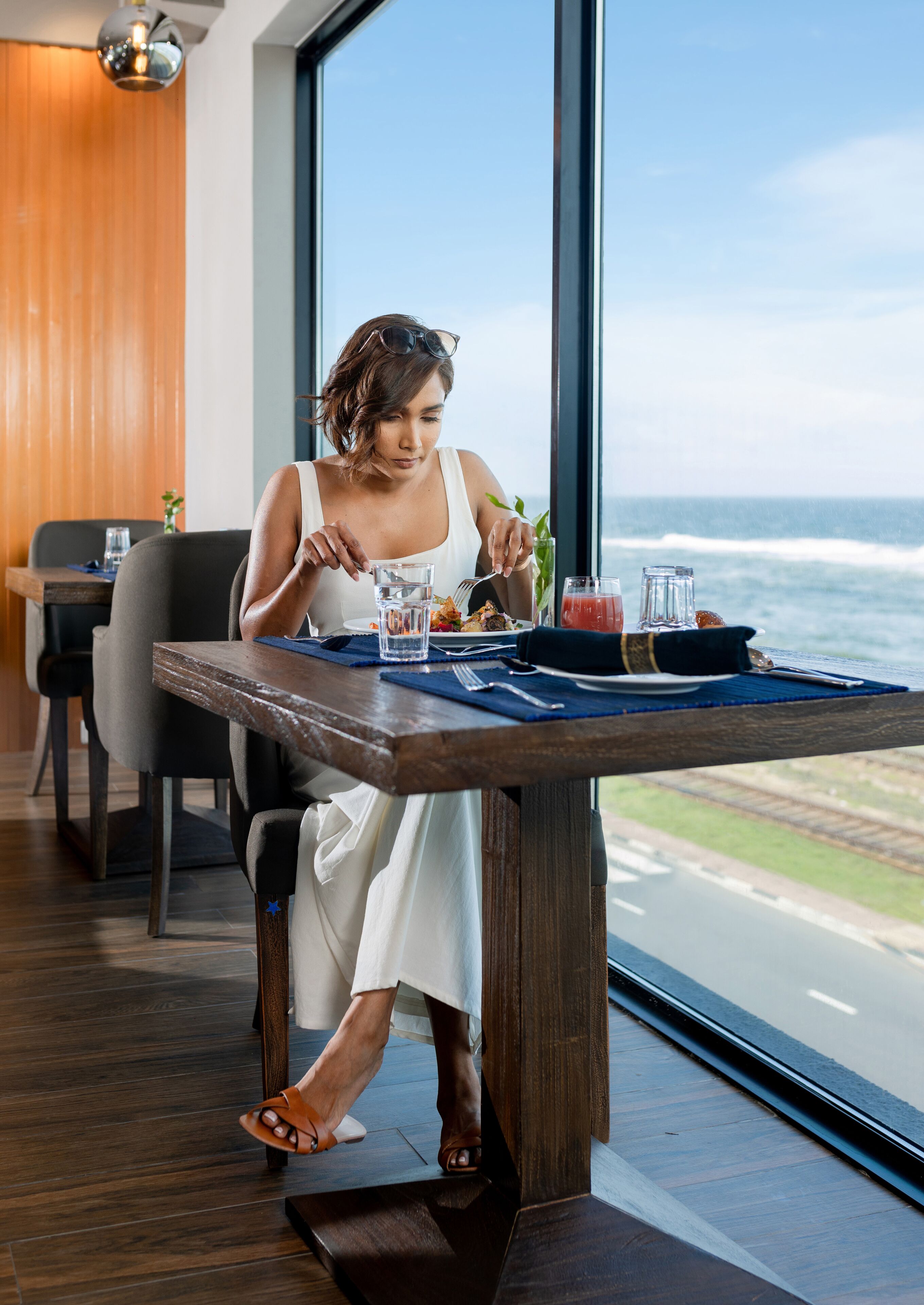A woman dining at a table with a view of the ocean.