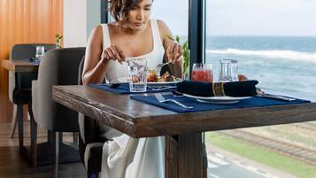 A woman dining at a table with a view of the ocean.