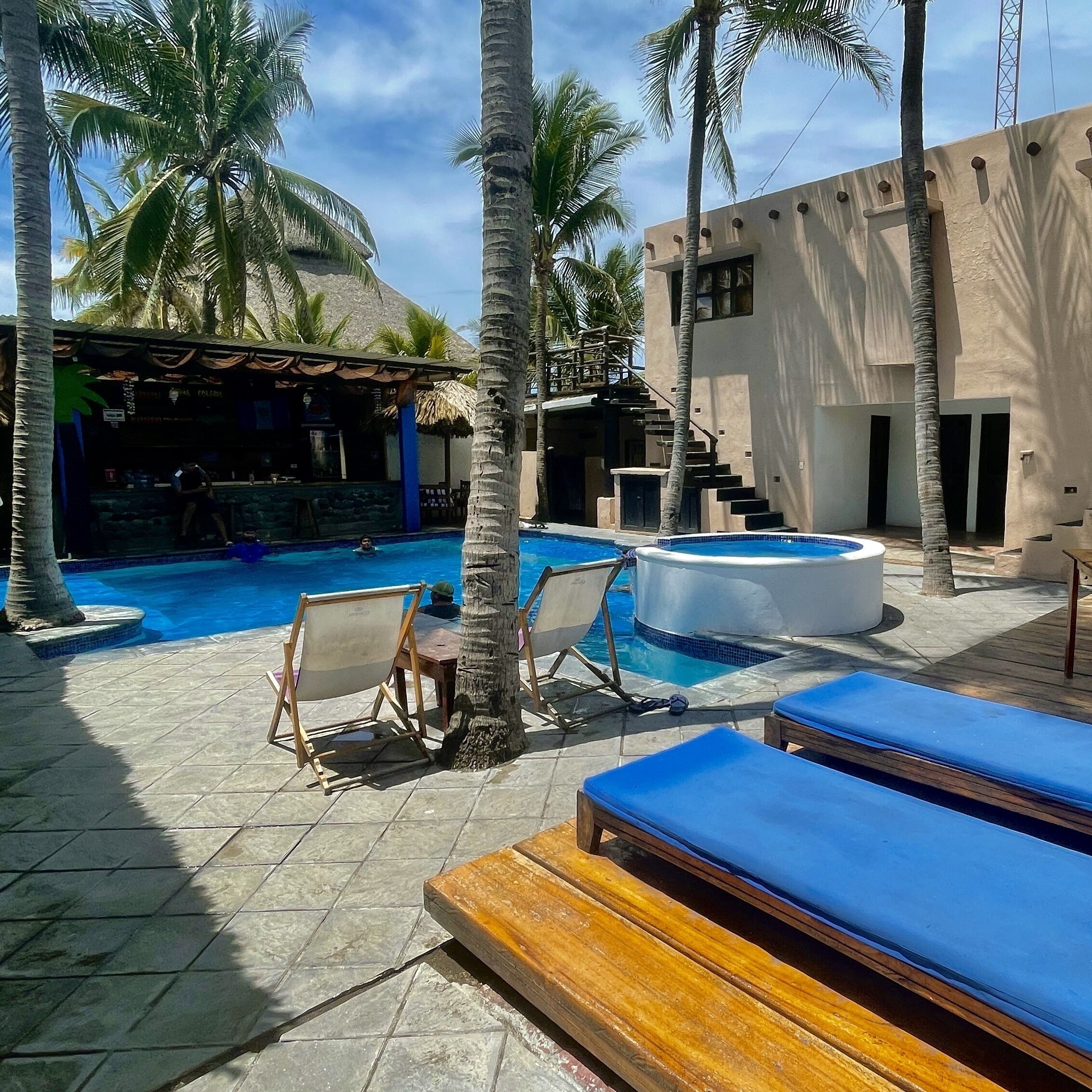 A pool area with lounge chairs and a hot tub.