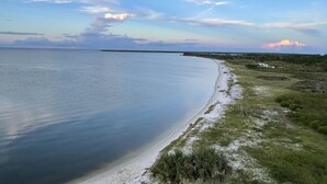 Paesaggio costiero con spiaggia sabbiosa e dune erbose.