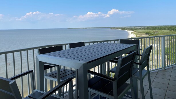 Un balcone con tavolo e sedie che si affaccia su una spiaggia.