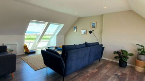 Un salon moderne avec un canapé bleu foncé, une petite table ronde et une grande verrière.