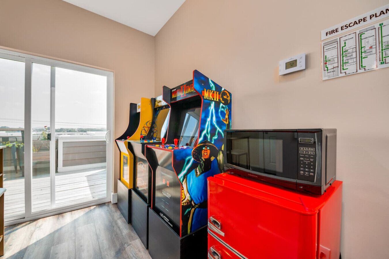 A room with a game console, a microwave, and a fire escape plan on the wall.
