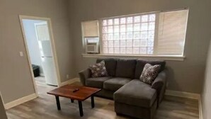 Sala de estar com sofá, apoio para os pés, mesa de centro e ventoinha no teto.