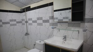 Casa de banho com sanita, lavatório e chuveiro.