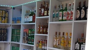 Een slijterij met schappen vol flessen en blikjes drank.