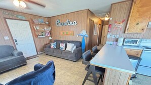 A cozy living area with a sofa, a dining table, and a kitchen area with a toaster. - DOGS AND DAY DREAMS! August & September dates available (Kill Devil Hills)