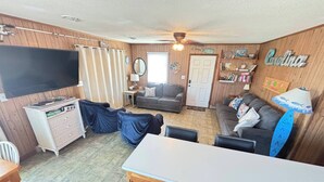 A living room with a television, sofa, and a wooden cabinet. - DOGS AND DAY DREAMS! August & September dates available (Kill Devil Hills)