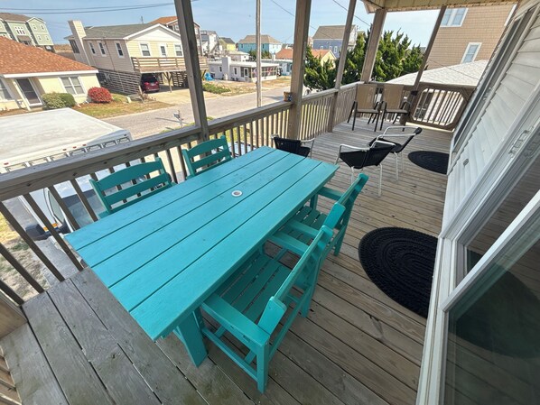 A turquoise deck with a table and chairs, overlooking a residential street.