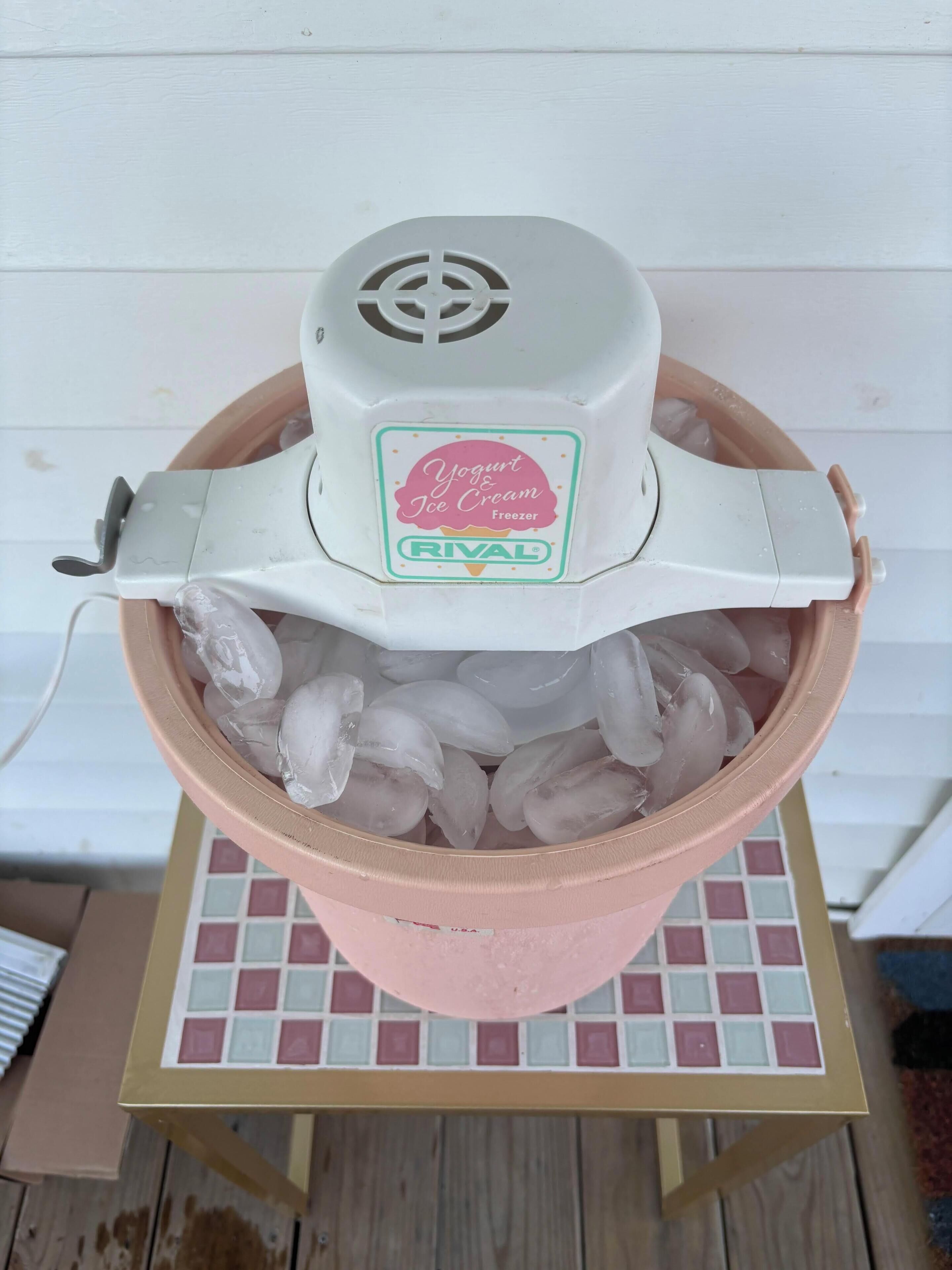 A yogurt and ice cream freezer with a pink container filled with ice cubes.