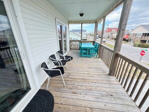 A covered porch with a table and chairs, a stop sign, and a view of the street.