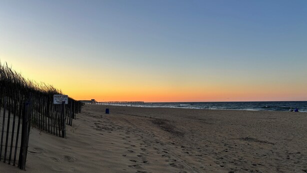 A beach with a wooden fence, a pier in the background, and footprints in the sand. - DOGS AND DAY DREAMS! August & September dates available (Kill Devil Hills)