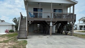 A two-story building with a balcony and a staircase leading to the upper floor. - DOGS AND DAY DREAMS! August & September dates available (Kill Devil Hills)