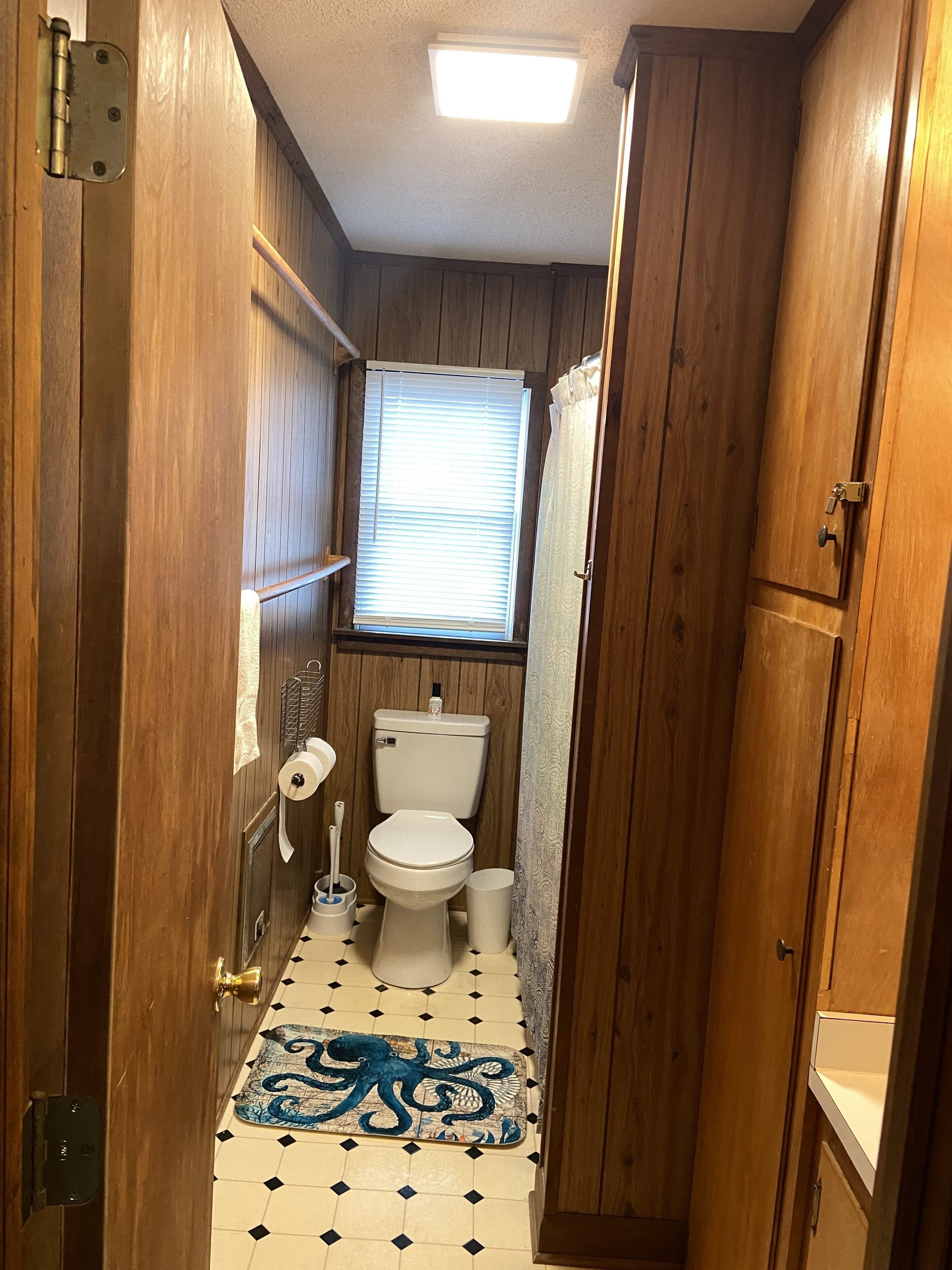 Une petite salle de bain étroite aux murs en bois et au sol carrelé.