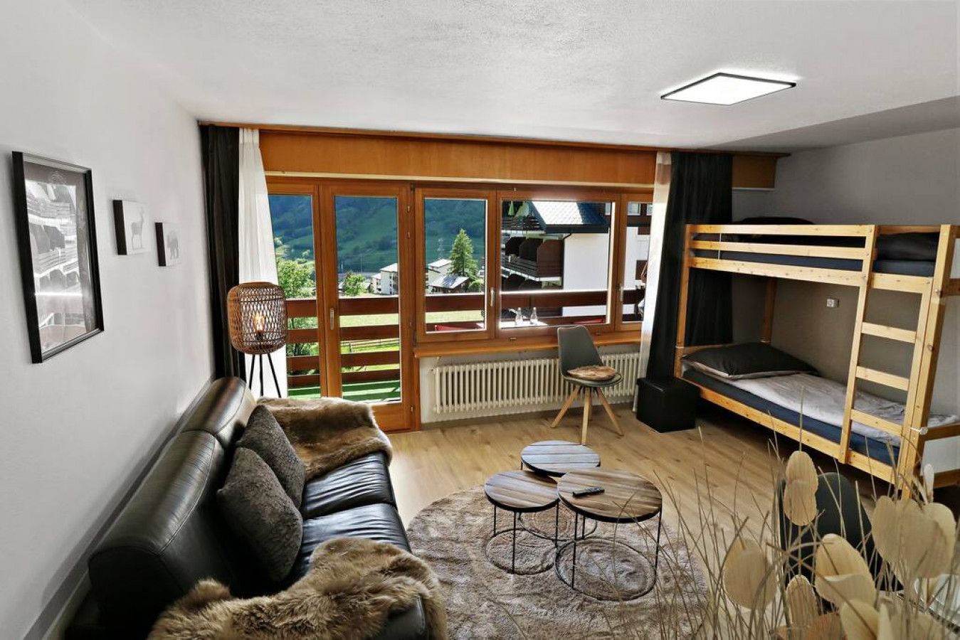Una habitación acogedora con sofá, una mesita, litera y vistas al exterior.