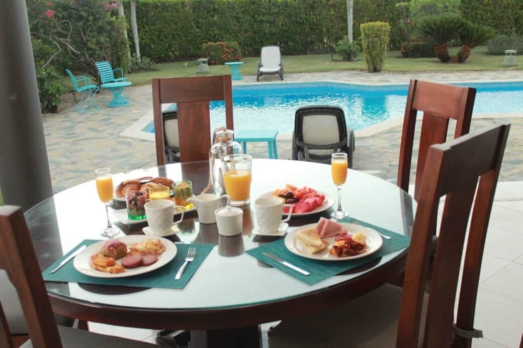 Une table de petit-déjeuner installée à l’extérieur, avec une piscine en arrière-plan.