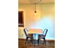 A dining area with a table and two chairs, lit by a hanging fixture.