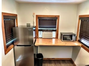Enjoy meal preparation in this kitchenette with a refrigerator, microwave, and trash bin.