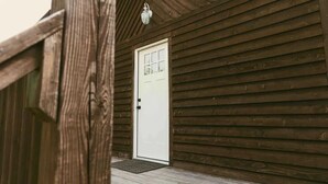 Una cabaña de madera con una puerta blanca y un pequeño porche.