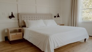 A neatly arranged bedroom with a large bed, two bedside tables, and a window with curtains.
