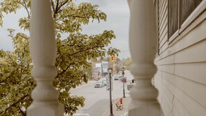 A view from a balcony with a street in the background, including a sidewalk and a crosswalk.