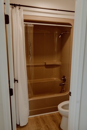 A bathroom with a bathtub, toilet, and shower curtain. - The Main Hen House, trendy downtown Main St location, walk to everything! (Lexington)