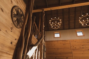Un interior rústico con vigas de madera, una noria grande y dos candelabros.