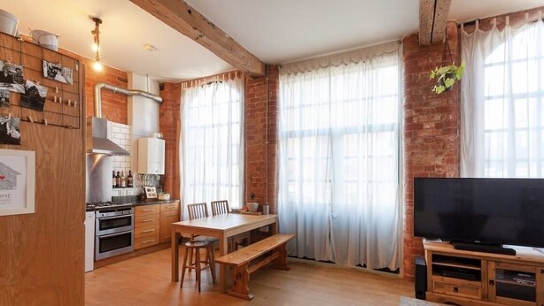 A cozy kitchen with wooden cabinets, a dining table, and a TV. - Apartment 74 (Nottingham)