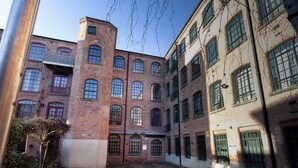 A courtyard with a brick building featuring large windows and a central tower. - Apartment 74 (Nottingham)