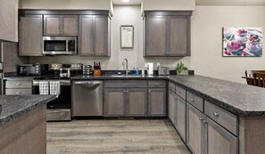 Una cocina moderna con armarios de madera oscura, electrodomésticos de acero inoxidable y encimera de granito.