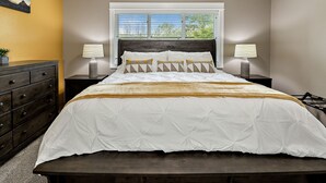 A bedroom with a bed, two bedside tables with lamps, a dresser, and a window with blinds. - Galaxy-Themed, Fastest WiFi, 3 King Beds Home (Medford)