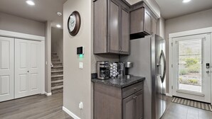 A modern kitchen with dark wood cabinets, a stainless steel refrigerator, and a built-in coffee maker. - Galaxy-Themed, Fastest WiFi, 3 King Beds Home (Medford)