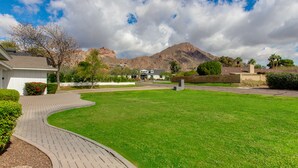 A well-maintained lawn with a curved pathway leading to a building. - Beautiful Furnished Arcadia Home with Camelback View Off Exeter (Phoenix)