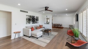 A spacious living room with a sofa, ottoman, and coffee table, a dining area with chairs, and a ceiling fan. - Beautiful Furnished Arcadia Home with Camelback View Off Exeter (Phoenix)