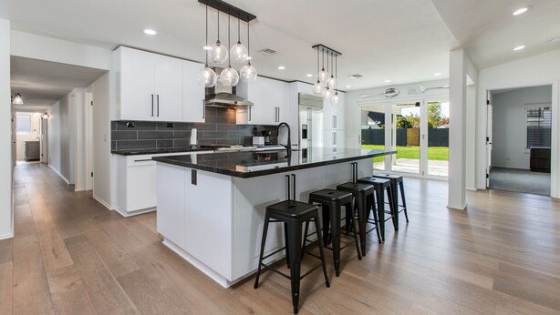 A modern kitchen with a large island, black bar stools, and pendant lighting. - Beautiful Furnished Arcadia Home with Camelback View Off Exeter (Phoenix)