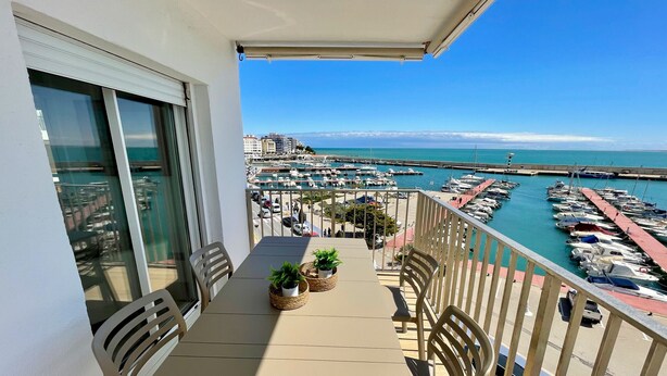 A balcony with a table, chairs, and potted plants. - APTO PANORAMIC (Ampolla)