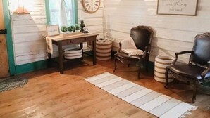 A cozy room with wooden flooring, a wooden table with a clock, two chairs, a rug, and a wall with a motivational quote. - Secluded, Cozy Cabin Getaway (Monroe)