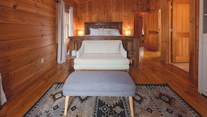 A wooden cabin room with a bed, a sofa, and a bench. - Chilhowee-Big log cabin with hot tub by the Ocoee (Benton)