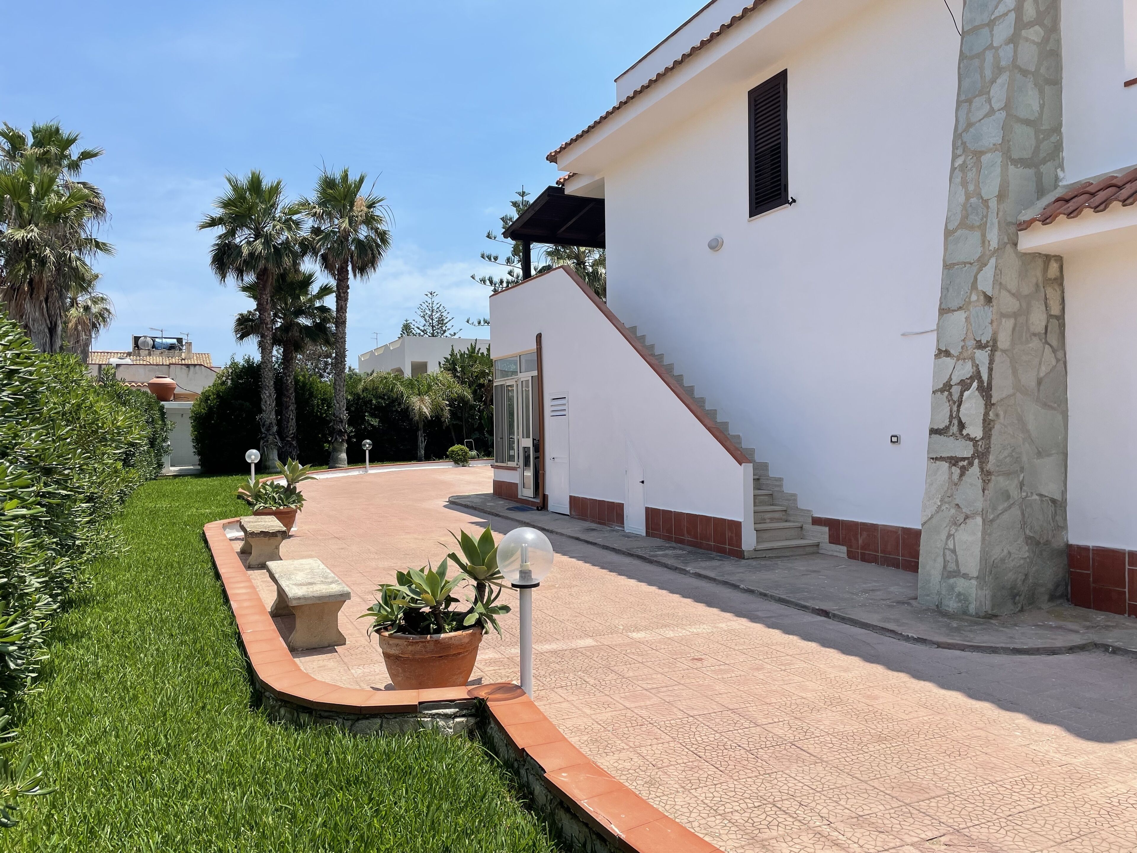 Uma casa moderna com uma coluna de pedra, escadaria e um gramado bem cuidado.