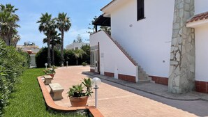 A modern house with a stone column, a staircase, and a well-maintained lawn. - Apartment San Lorenzo in Villa (San Lorenzo)