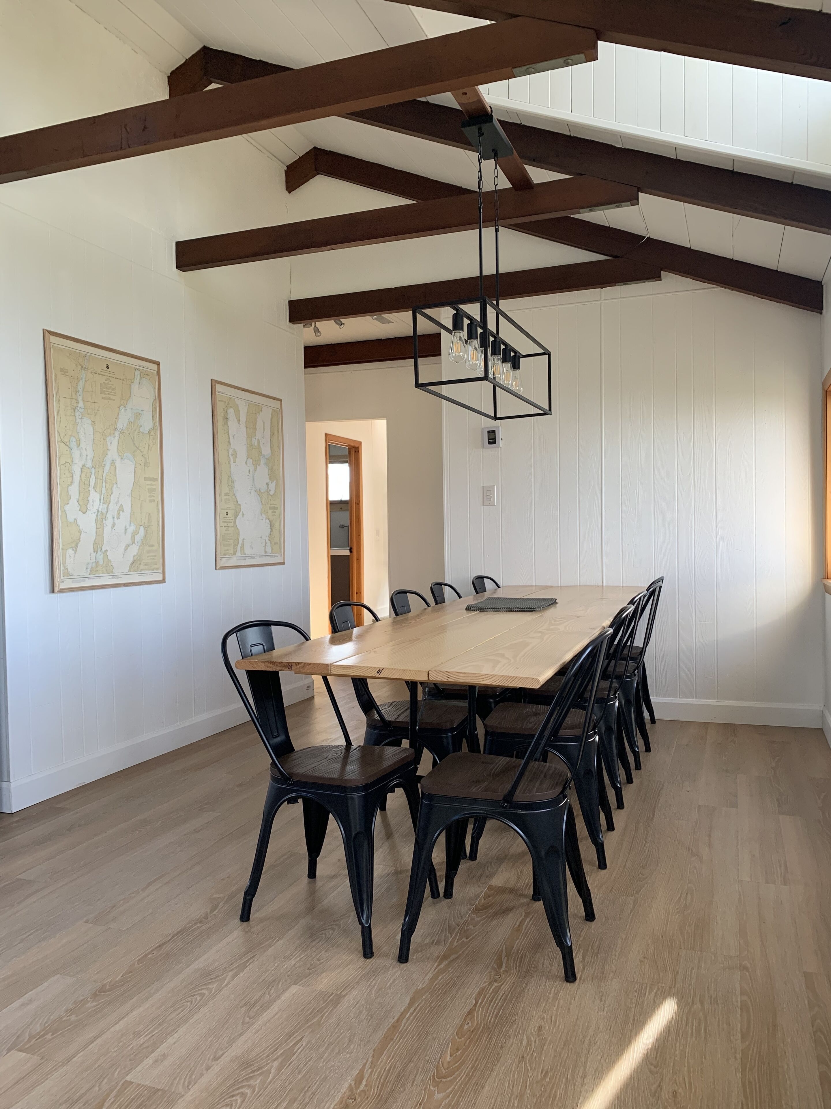 Ein Esszimmer mit einem großen Holztisch, schwarzen Stühlen und einer Pendelleuchte.