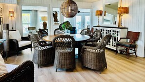 A dining area with wicker furniture, a round table, and pendant lighting. - Pet Friendly - Ocean View Huge Deck -  Across from Beach - Walk to Center St (Folly Beach)