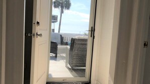 A hallway leading to a balcony with a view of the beach and palm trees. - Pet Friendly - Ocean View Huge Deck -  Across from Beach - Walk to Center St (Folly Beach)