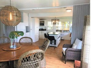 Enjoy meals in the central dining area with a wooden table and wicker chairs.