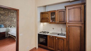 A compact kitchen with wooden cabinets, a stove, and a sink.