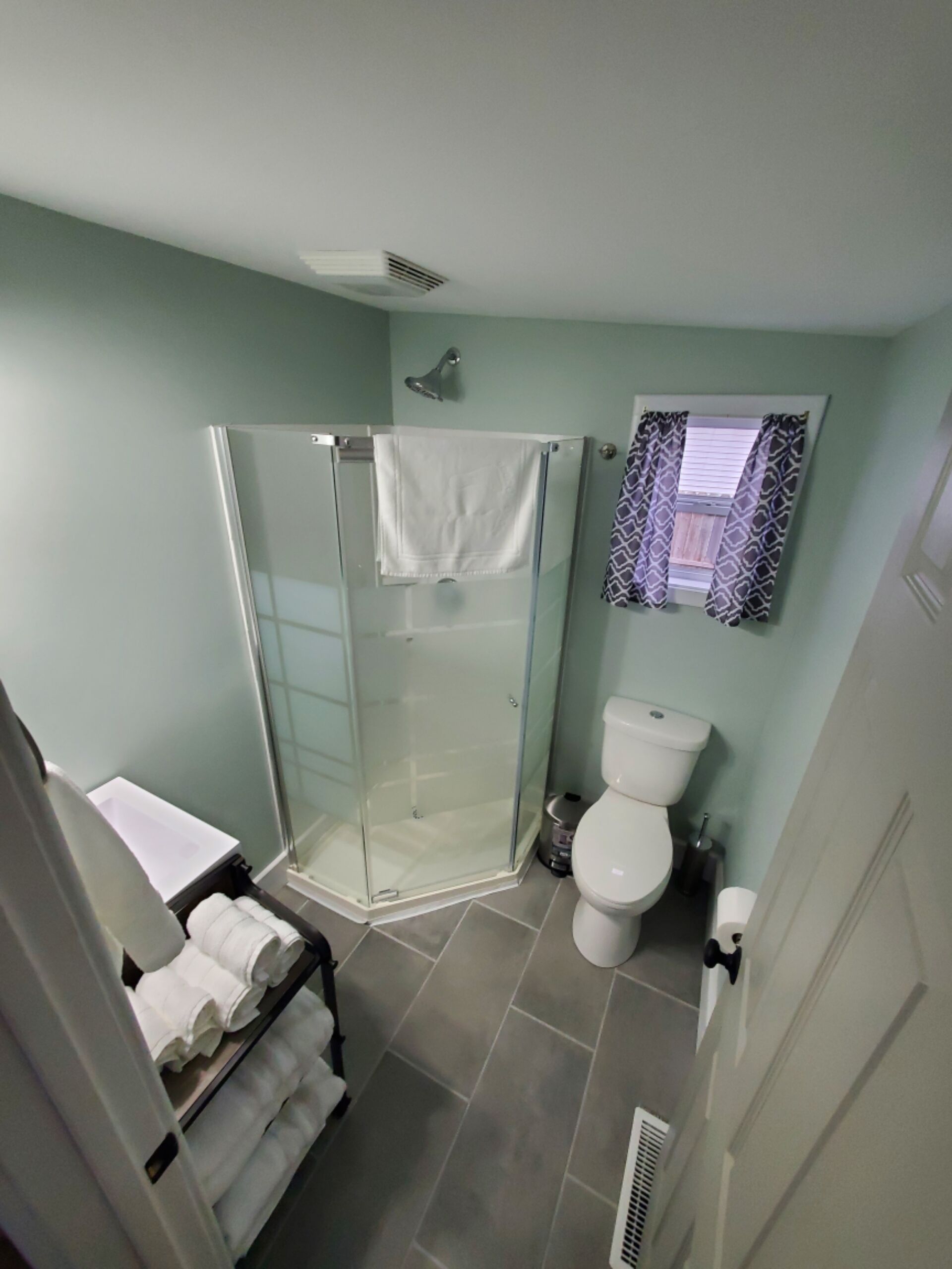 Ein Badezimmer mit Duschkabine, Toilette und Handtuchhalter mit gefalteten Handtüchern.
