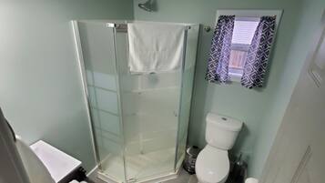 Ein Badezimmer mit Duschkabine, Toilette und Handtuchhalter mit gefalteten Handtüchern.