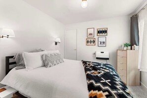 Ein Schlafzimmer mit einem Bett, Nachttischlampen, einem Schminktisch und Wandbildern.