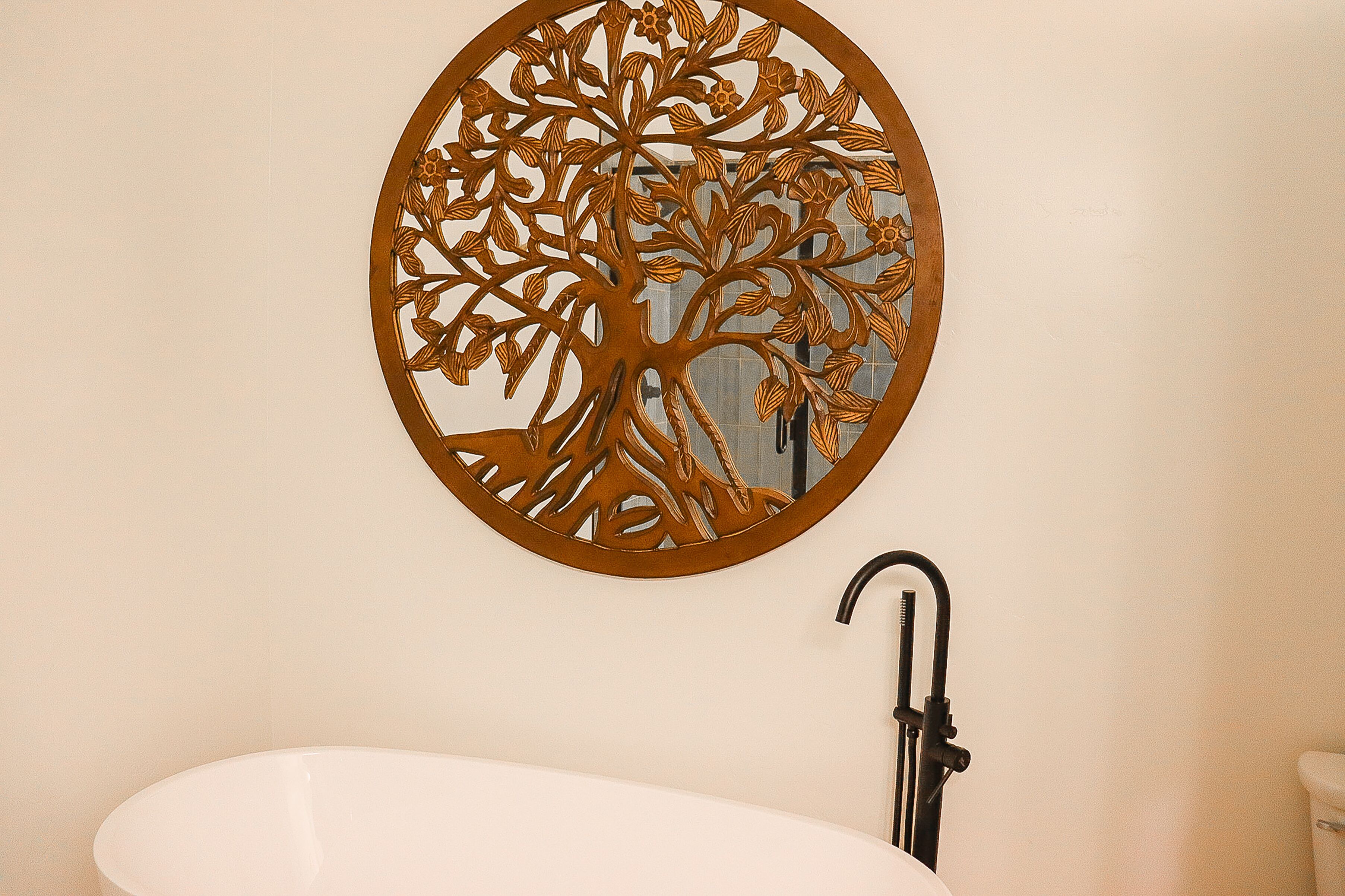 Um banheiro com uma banheira branca, uma torneira preta e um detalhe decorativo na parede.
