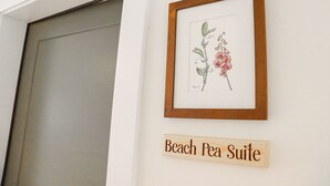 A framed botanical illustration and a wooden sign indicating a room named 'Beach Pea Suite'. - The Wildflower Inn (Gold Beach)